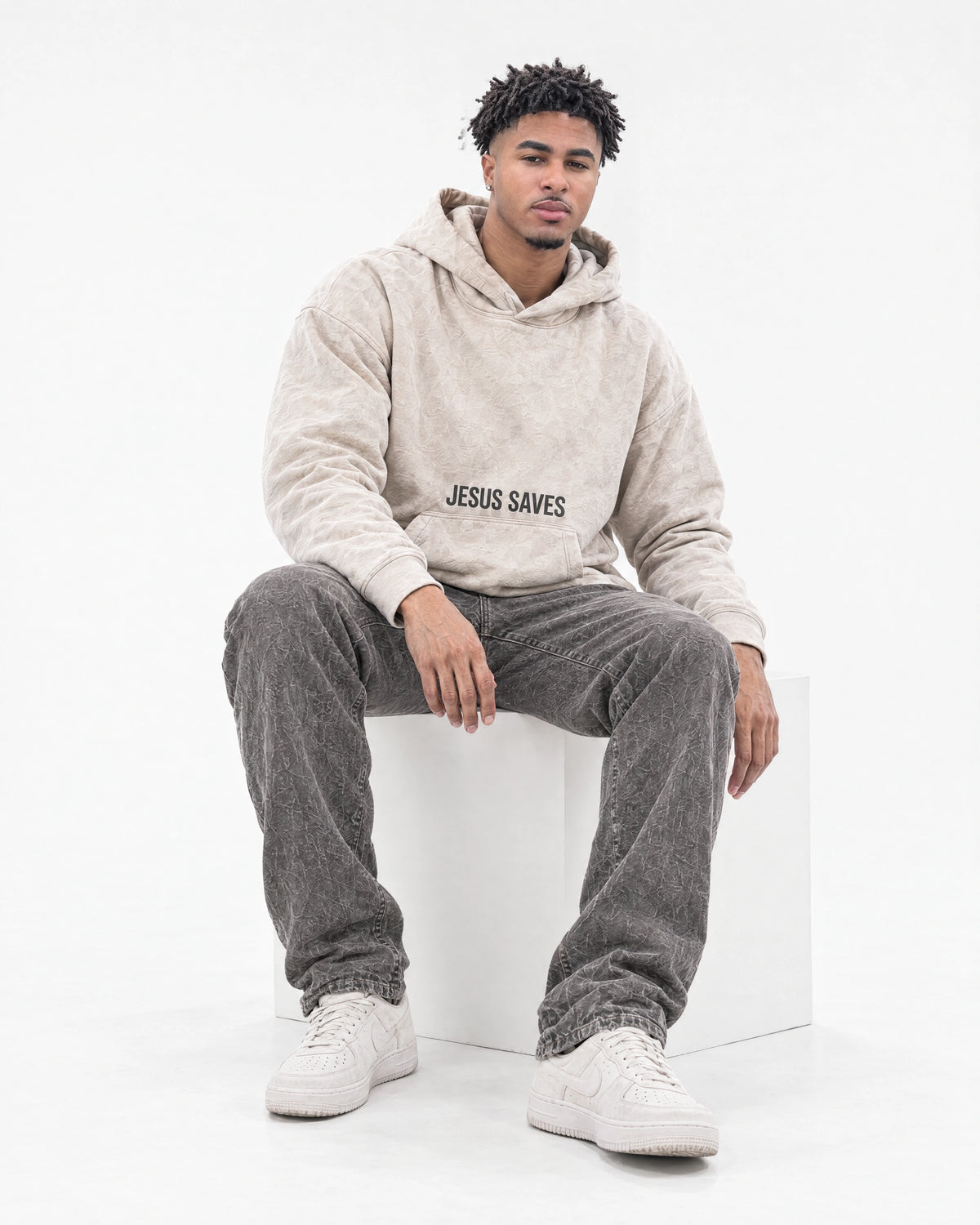 Isaiah seated in a white studio wearing a JSCA hoodie